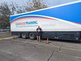 Person standing beside a large training vehicle with "GS Driver Training" branding, emphasizing commercial driver training and CPC qualification in Berkshire.